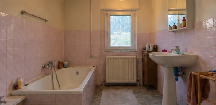 Salle de bain avant rénovation : faïence rose des années 80, baignoire d'angle